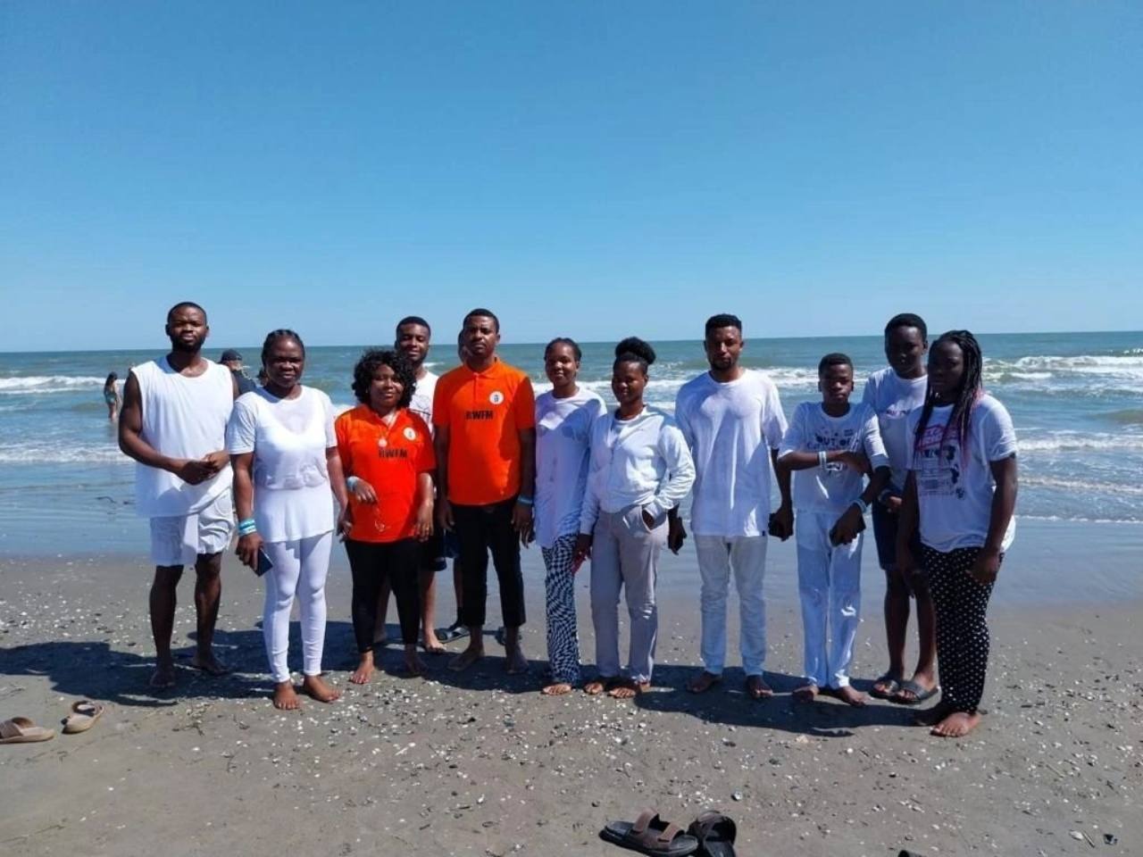 Rodwater baptism participants standing together on the beach beside the sea