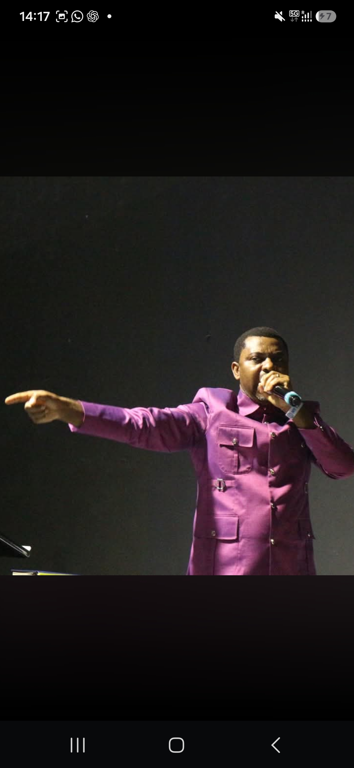 A minister preaching in a purple jacket